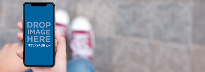 Woman Using an iPhone 11 Pro Mockup While Walking on the Street