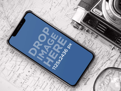 iPhone X Mockup Lying on a Map Next to a Vintage Camera a17501