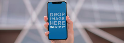 iPhone 11 Pro Mockup Being Used Outside a Modern Building