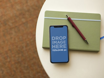 iPhone X Mockup Lying on a Table with a Notebook and a Pen a17540