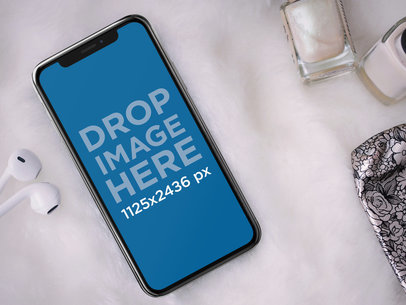 iPhone X Mockup Lying Next to Nail Products and Earphones a17545