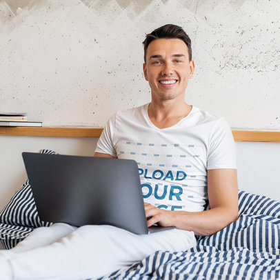 V-Neck Tee Mockup of a Happy Young Man Working in Bed