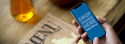 iPhone X Mockup Being Held on a Vintage Coffee Table a17626