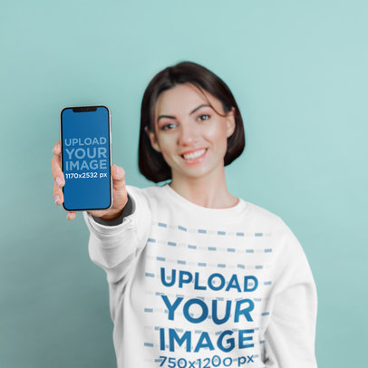Sweatshirt Mockup Featuring a Smiling Woman Holding an iPhone
