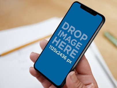 Man Holding an iPhone 11 Pro Mockup on a Desk