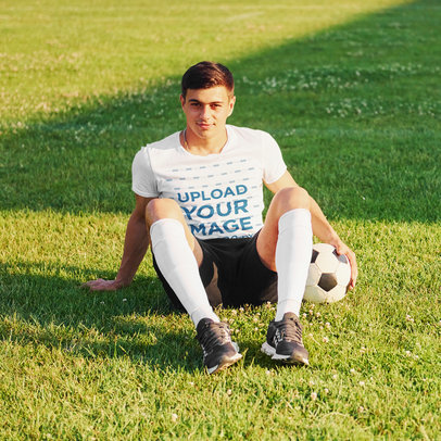 T-Shirt Mockup of a Soccer Playing Sitting on a Field