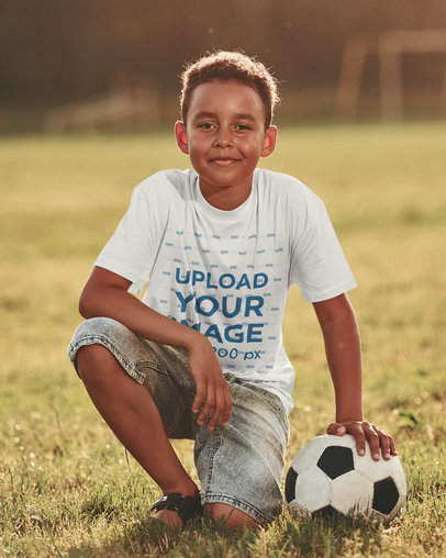 Round-Neck Tee Mockup of a Happy Boy Posing in a Soccer Field