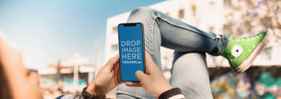 Mockup of a Girl Using an iPhone X While Taking a Break at a Skatepark a17679