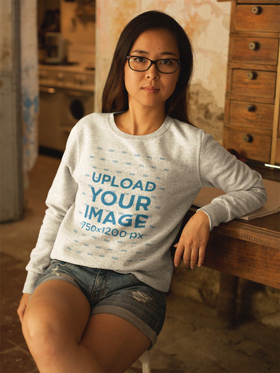 Asian Girl Wearing a Crew Neck Sweatshirt Mockup While Lying Against a Vintage Desk a17605