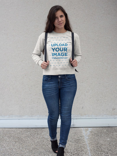 Pretty Woman with Backpack Wearing a Crewneck Sweatshirt Template While Standing Against a White Wall