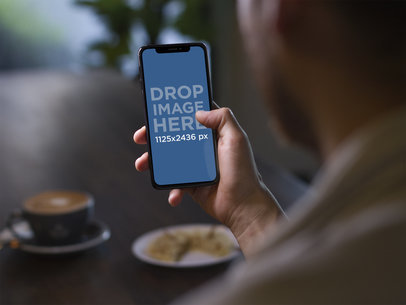 Man Playing Games in an iPhone X While Taking a Coffee a17775