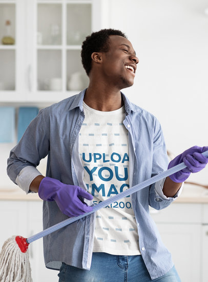 Tee Mockup of a Joyful Man Playing Air Guitar with a Cleaning Mop at Home