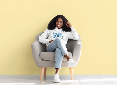 Hoodie Mockup Featuring a Happy Woman Sitting on an Armchair