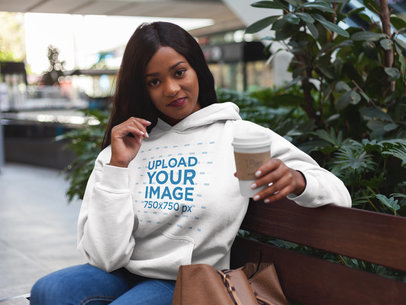 Mockup of a Woman Having a Coffee While Wearing a Pullover Hoodie 