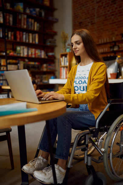 T-Shirt Mockup of a Woman Using a Wheelchair and Working on Her Computer