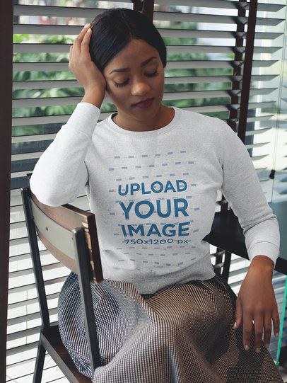 Mockup of a Woman Wearing a Crew Neck Sweatshirt while Sitting at a Diner Restaurant 