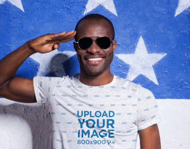 Heathered T-Shirt Mockup of a Happy Man with Sunglasses Doing a Military Salute