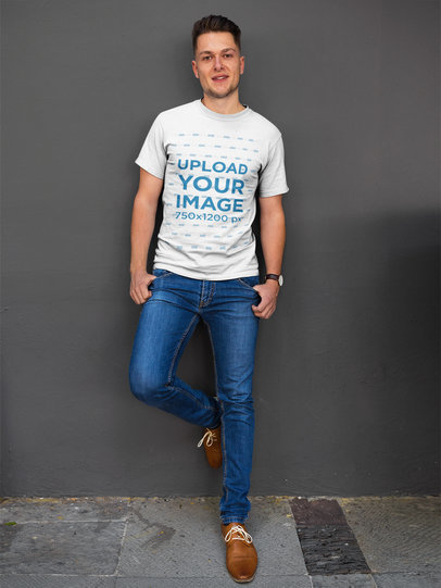 Happy Dude Wearing a Round Neck Tee Mockup while Lying Against a Gray Wall