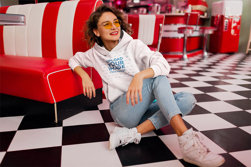 Pullover Hoodie Mockup of a Smiling Woman Posing in a 70s-Decorated Restaurant
