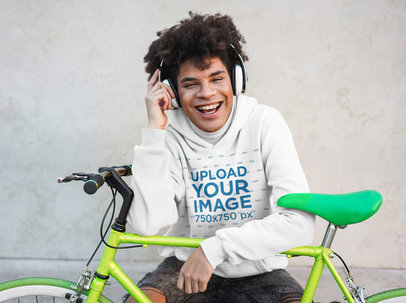 Pullover Hoodie Mockup Featuring a Man with Headphones Sitting Next to His Bike