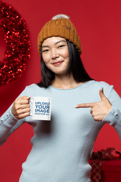 Christmas-Themed Mockup of a Woman Pointing at an 11 oz Coffee Mug
