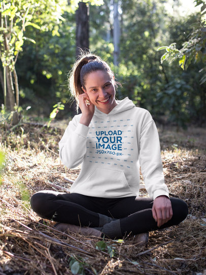 Happy Blonde Woman Sitting in the Forest Wearing a Pullover Hoodie Mockup