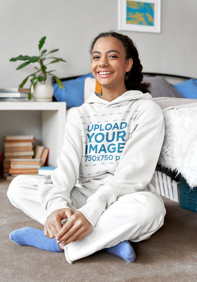 Pullover Hoodie Mockup Featuring a Smiling Young Woman Sitting on the Floor