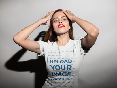 T-Shirt Mockup of a Woman Playing with her Hair Against a White Wall