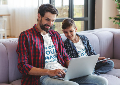 T-Shirt Mockup of a Smiling Man and His Son Using Gadgets at Home