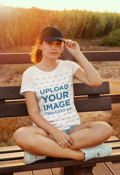 T-Shirt Mockup Featuring a Woman Sitting on a Bench at the Park