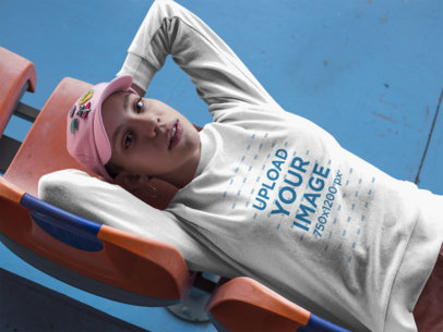 Girl Wearing a T-Shirt Mockup and a Pink Hat Lying on Plastic Chairs a18410