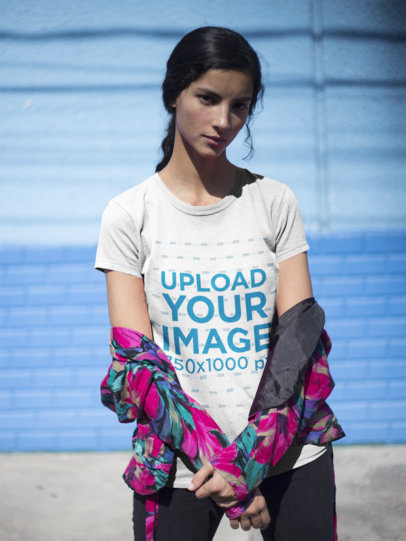Serious Woman Wearing a Tshirt Mockup Against a Blue Wall