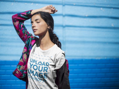 Woman Wearing a Round Neck Tee Mockup While Posing Against a Blue Wall