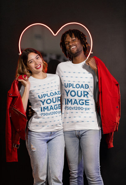 T-Shirt Mockup of a Couple Standing by a Valentine's Day Neon Heart Sign