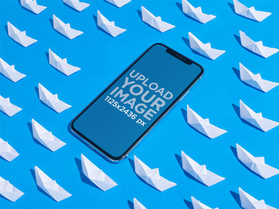 iPhone 11 Pro Mockup on a Blue Surface Surrounded by Paper Boats