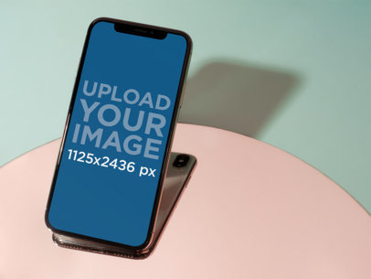 Creative Shot of an iPhone X Mockup on a Pink and Aqua Surface a19113