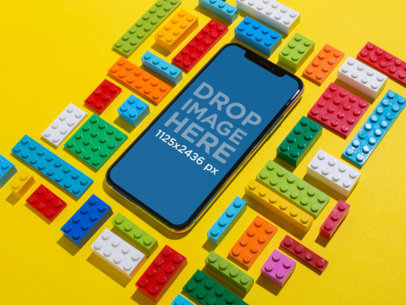 Black iPhone 11 Pro Mockup Lying on a Yellow Surface Surrounded by Blocks Toys
