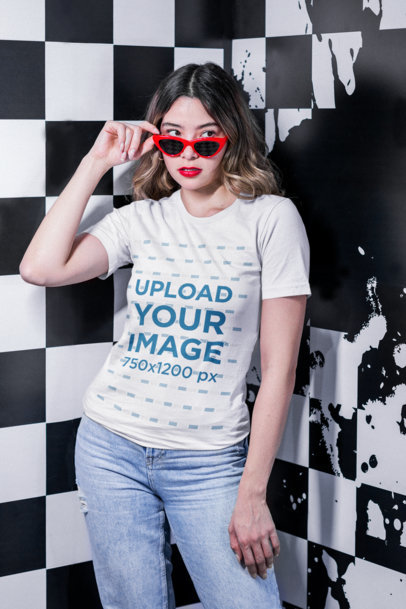 Round-Neck Tee Mockup of a Woman with Sunglasses Posing by a Checkered Background m20975