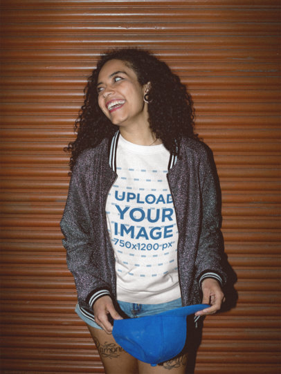 Happy Woman with Curly Hair Wearing a Crewneck Sweater Mockup while Standing Against a Metal Curtain a18824