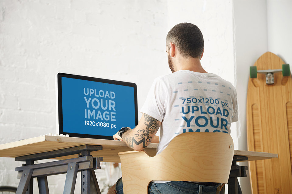 T-Shirt Mockup of the Back of a Tattooed Man Getting Ready to Work on His iMac