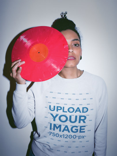 Serious Woman Wearing a Crewneck Sweatshirt Mockup Holding a Pink Vinyl Against her Eye