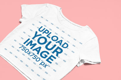 Simple Mockup of a Bella Canvas Crop Top Lying on a Flat-Color Surface