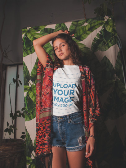 Woman Wearing a Tshirt Mockup with a Hand on her Hair Against a Printed Fabric