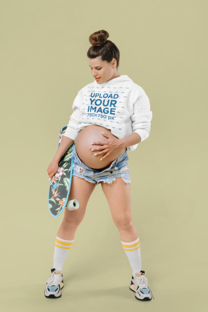 Hoodie Mockup of a Pregnant Woman Holding a Skateboard in a Studio