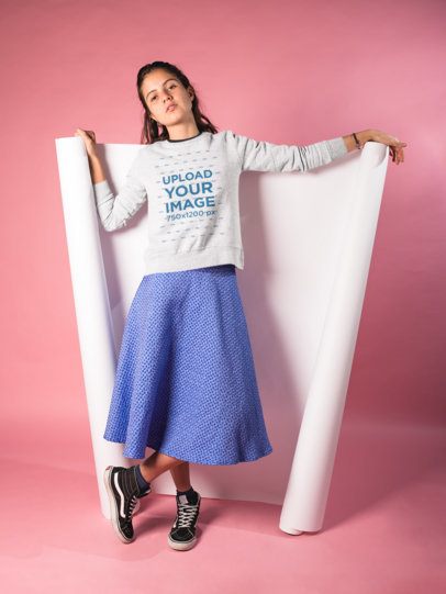 Woman Wearing a Crewneck Sweatshirt Mockup Lying over a Cyclorama in a Pink Room