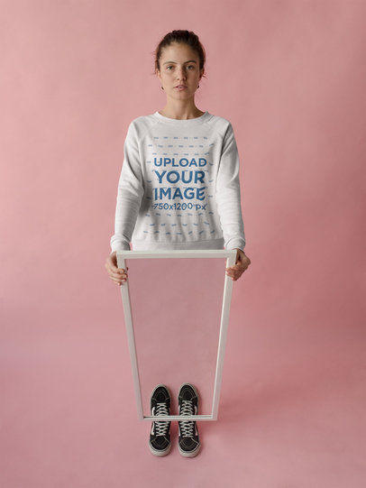 Beautiful Woman Wearing a Crewneck Sweatshirt Template in a Pink Room while Holding a Mirror