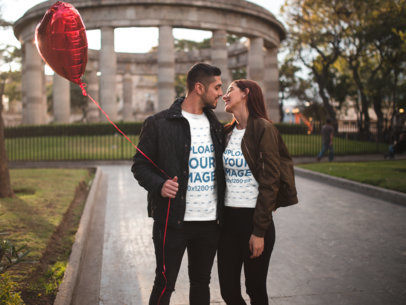 Happy Couple Wearing Valentine's Day T-Shirts Mockup while at a Park with a Heart Balloon