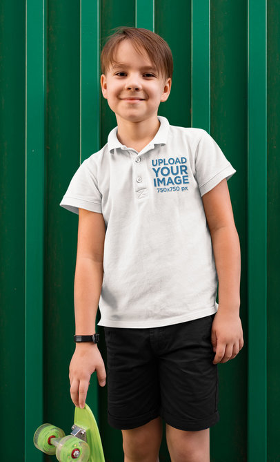 Mockup of a Boy Posing Next to a Small Skateboard While Wearing a Polo Shirt