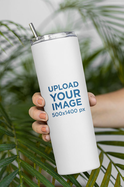 Mockup of a Woman Holding a Skinny Tumbler Featuring Palm Leaves in the Background