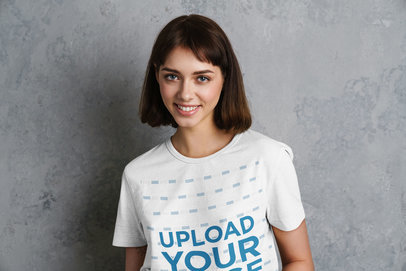 T-Shirt Mockup Featuring a Smiling Woman Posing Against a Gray Wall